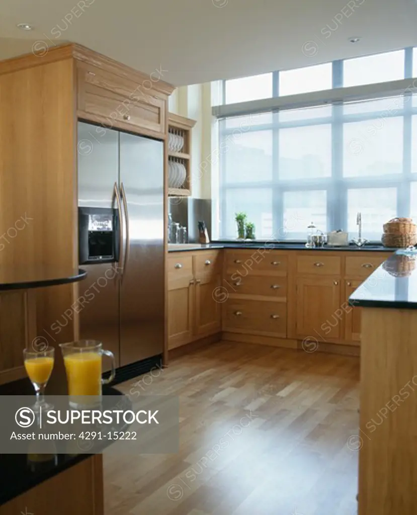 Stainless steel American-style refrigerator in modern kitchen with wooden flooring