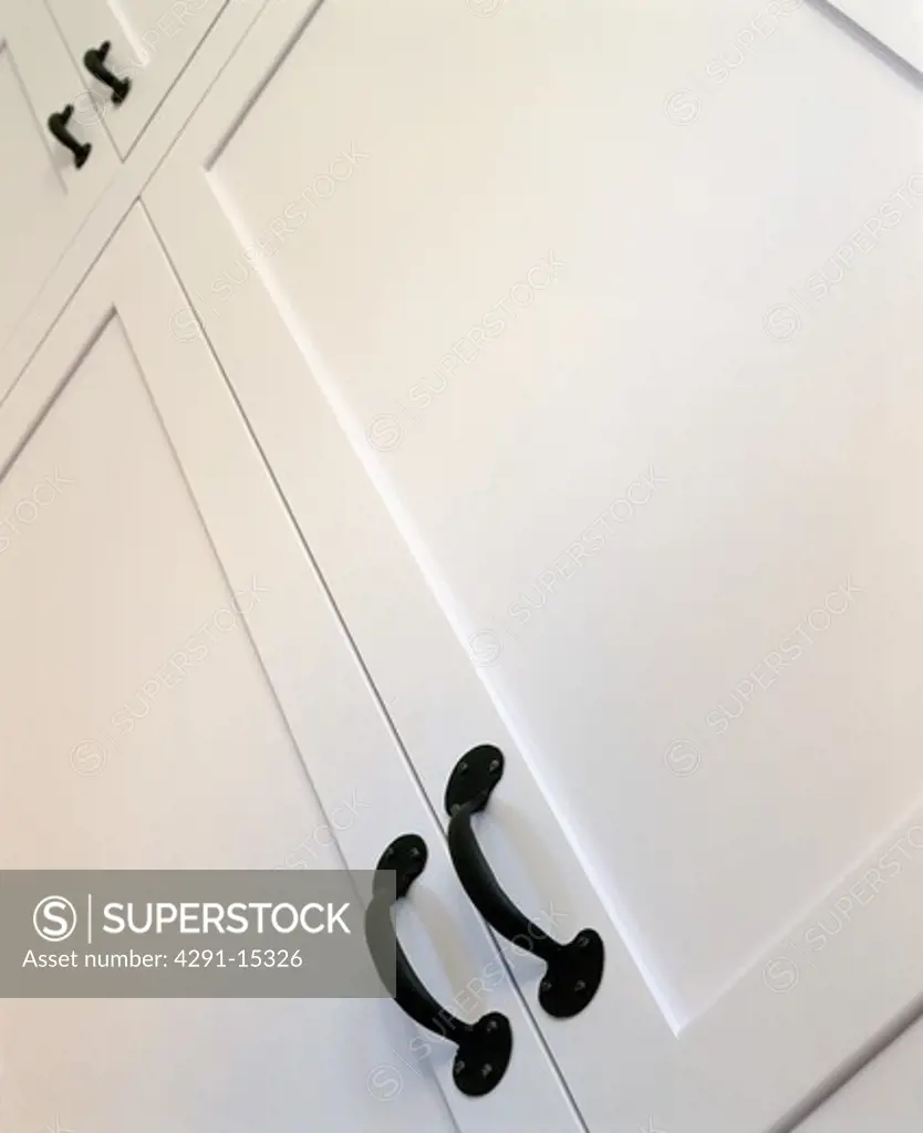 Close-up of white cupboard doors with black metal handles