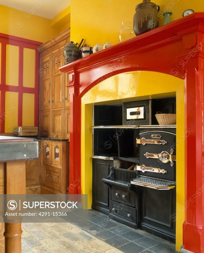 Close-up of black retro oven in red fireplace in yellow kitchen