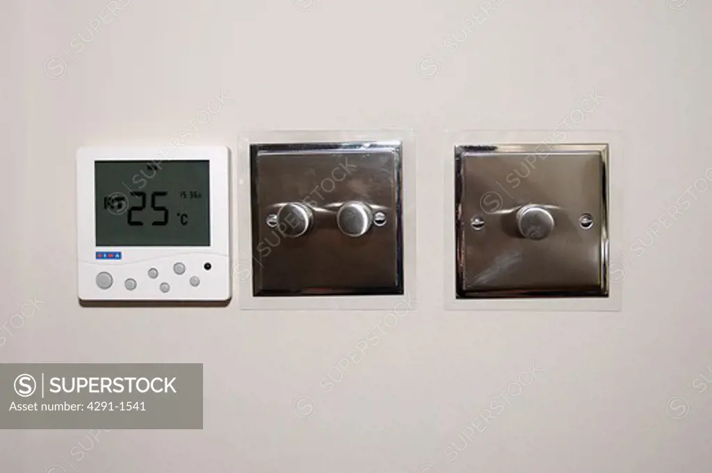 Close-up of thermostat and stainless steel light switches