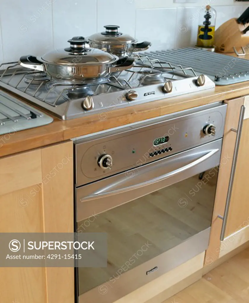 Close-up of saucepans on hob of stainless steel oven in modern kitchen