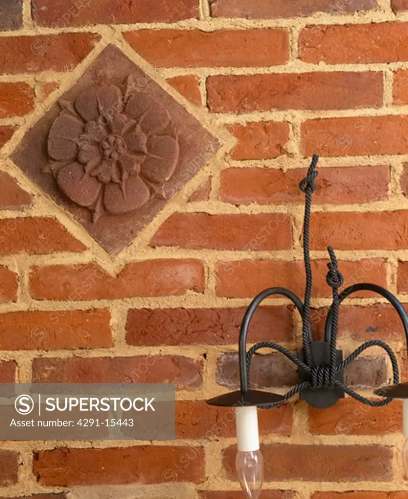 Close-up of black cast-iron wall-light on brick wall with decorative terracotta tile