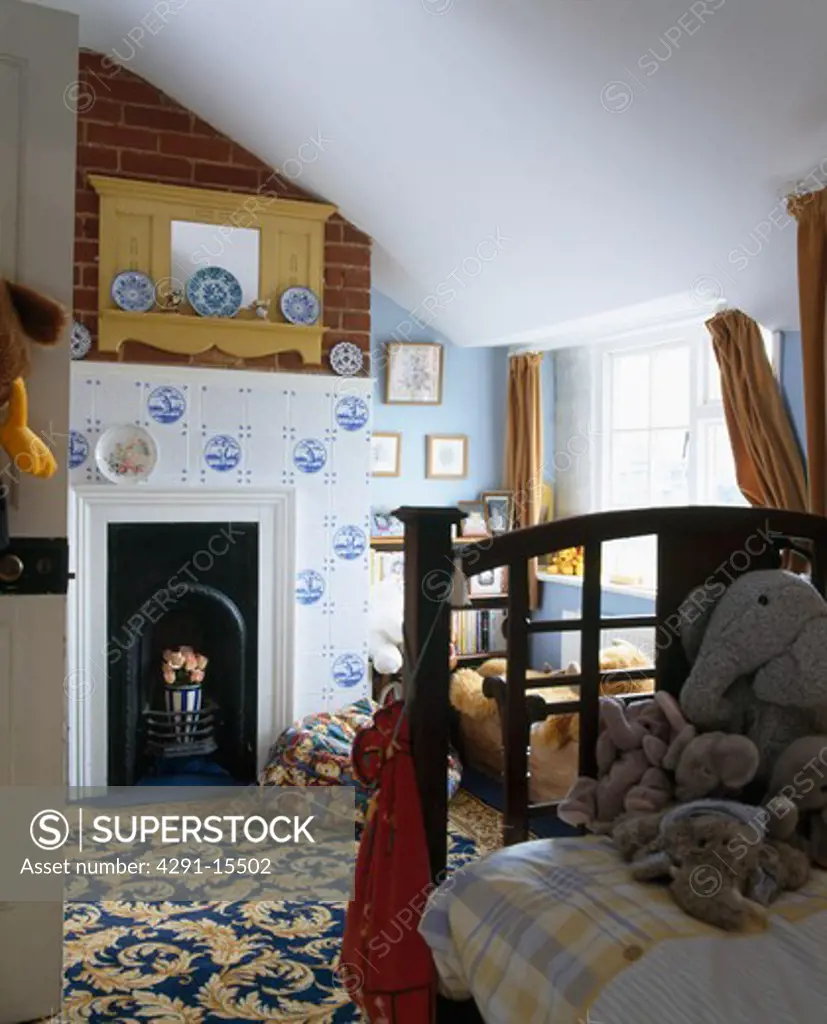 Blue and white Delft tiles on fireplace in child's pale blue attic bedroom with patterned carpet