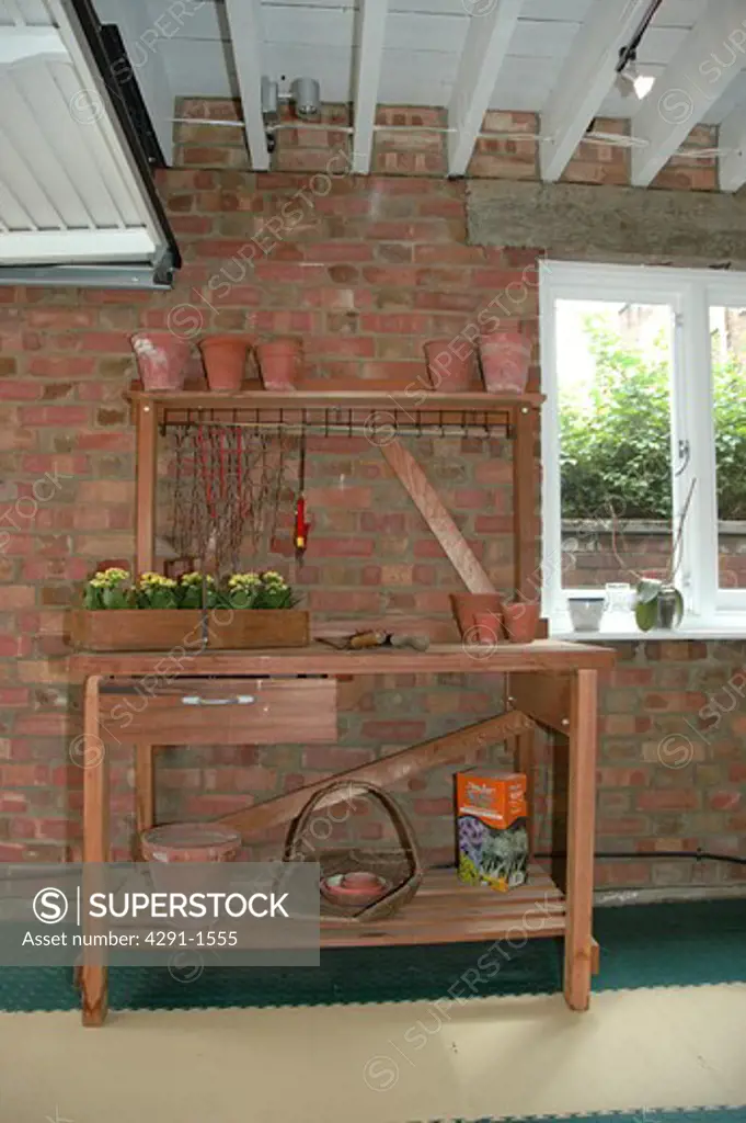 Terracotta pots and gardening equipment on wooden shelves in garage