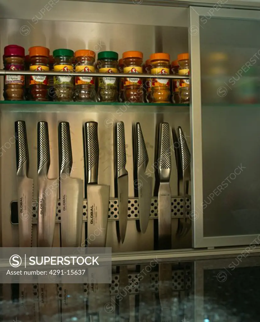 Close-up of kitchen knives stored on rack below herb and spice jars