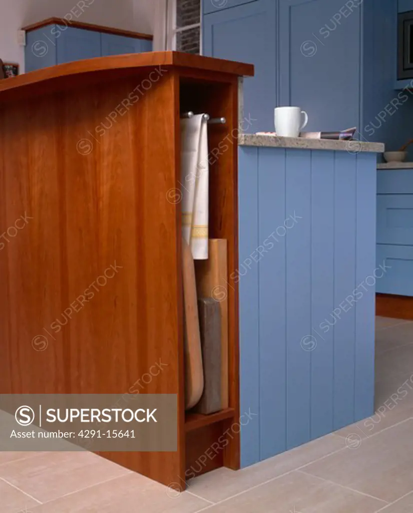 Close-up of fitted cherrywood storage unit with storage for trays and tea-towels