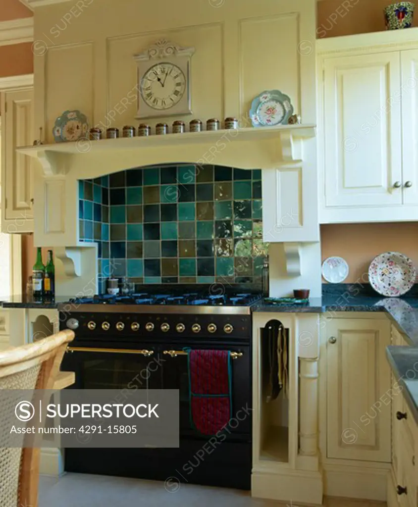 Green tiles on wall above black range oven in traditional country kitchen