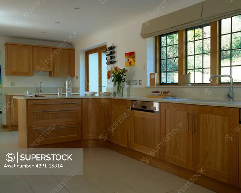 White ceramic floor tiles in modern white country kitchen with fitted wooden units