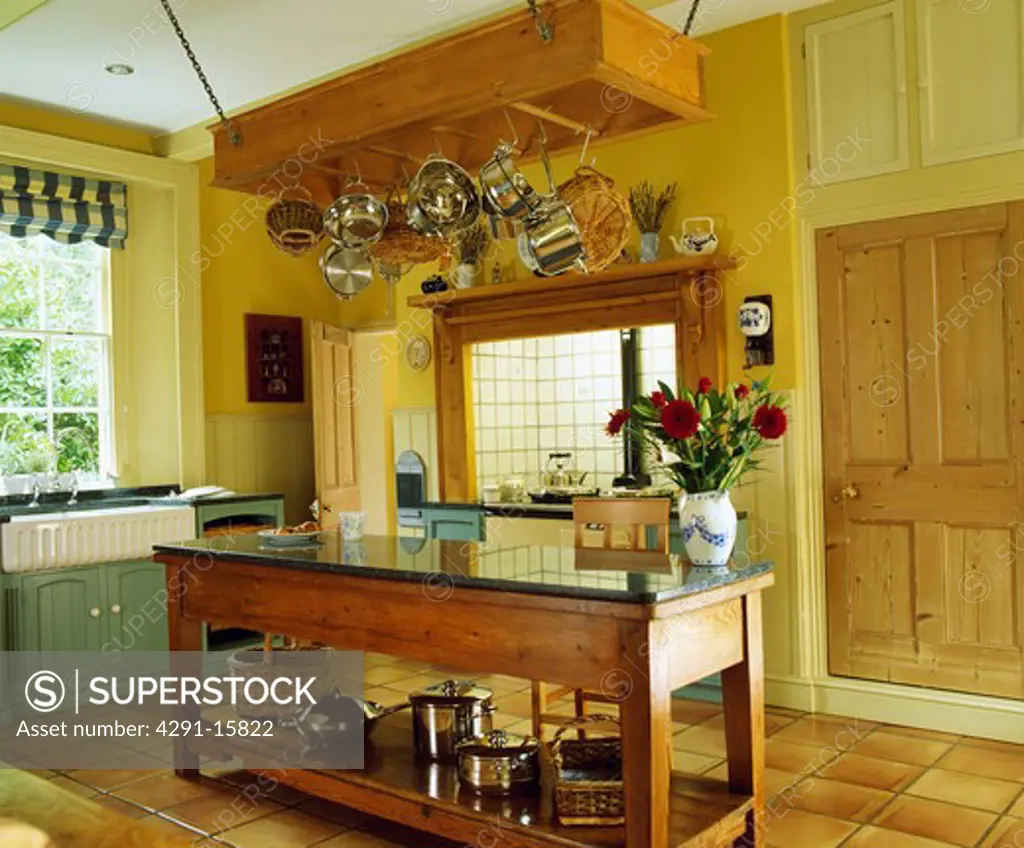 Traditional farmhouse style kitchen with butlers sink and central counter and hanging storage