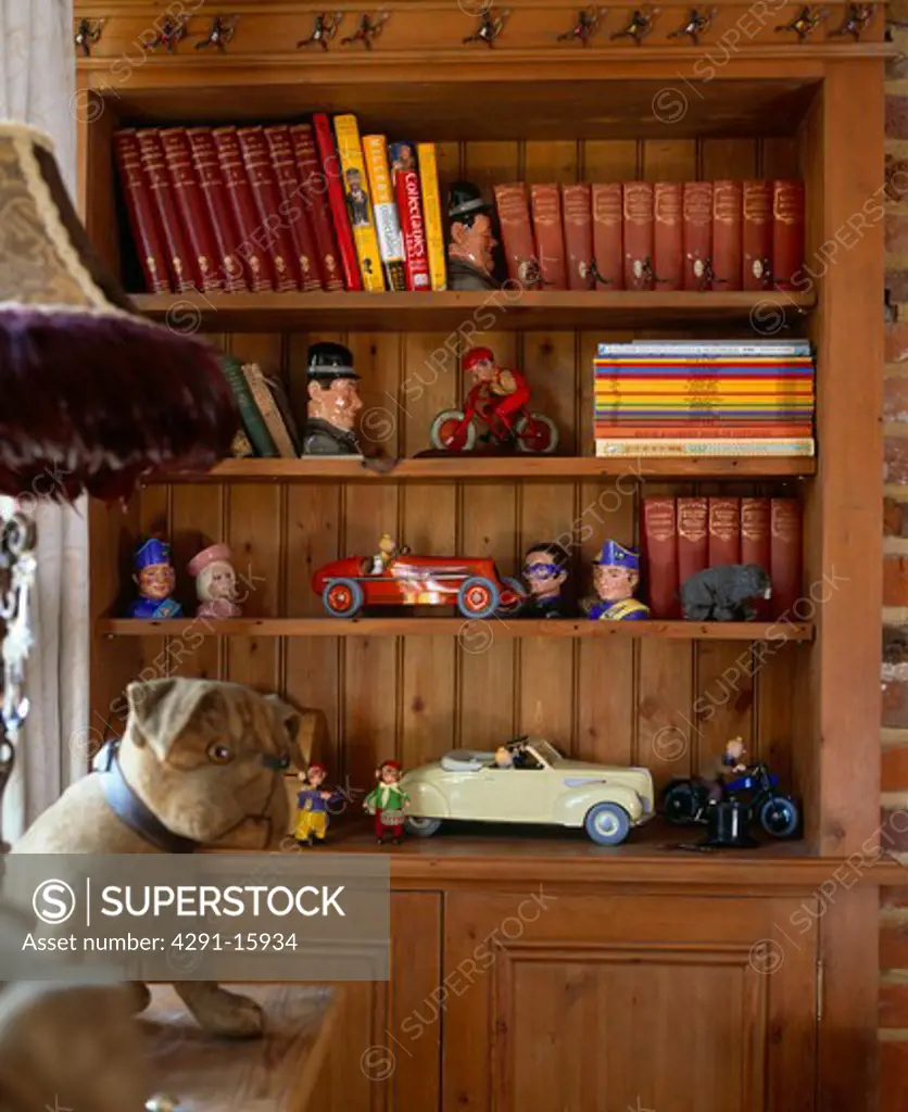 Collection of old toys on bookshelves in study with large toy dog