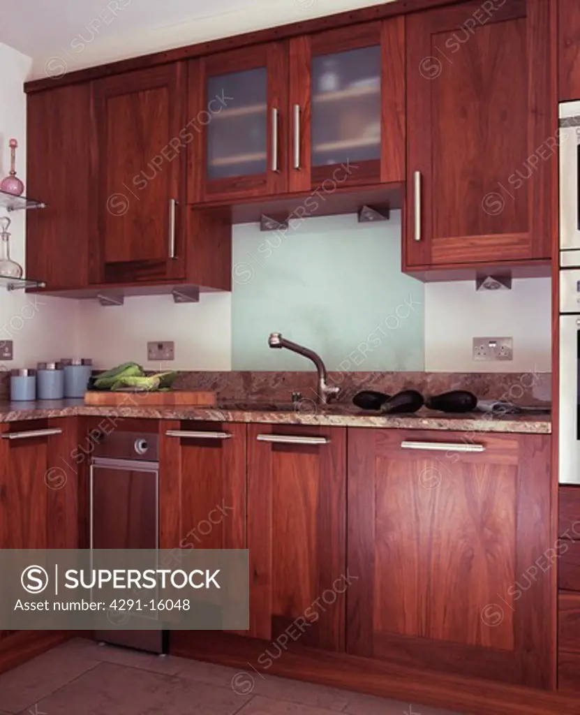 Glass splashback above sink in modern kitchen with dark wood fitted units