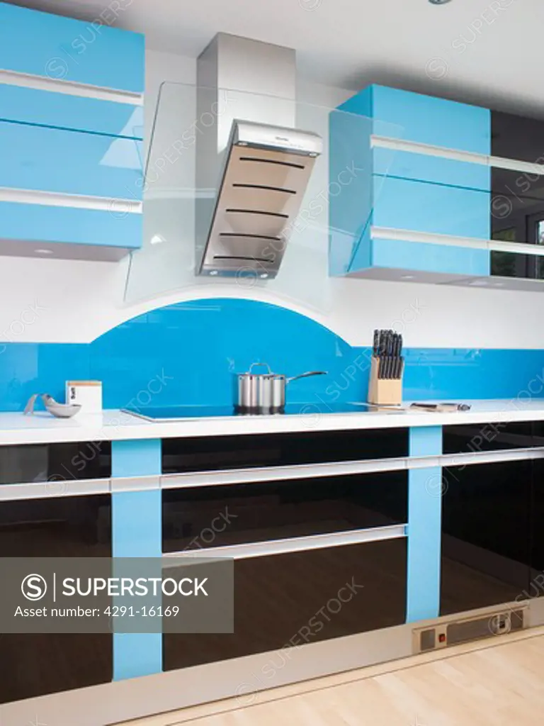 Stainless-steel extractor above hob in modern kitchen with fitted blue and black units