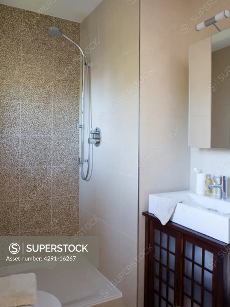Walk-in shower with pebble wall tiles and rectangular white basin