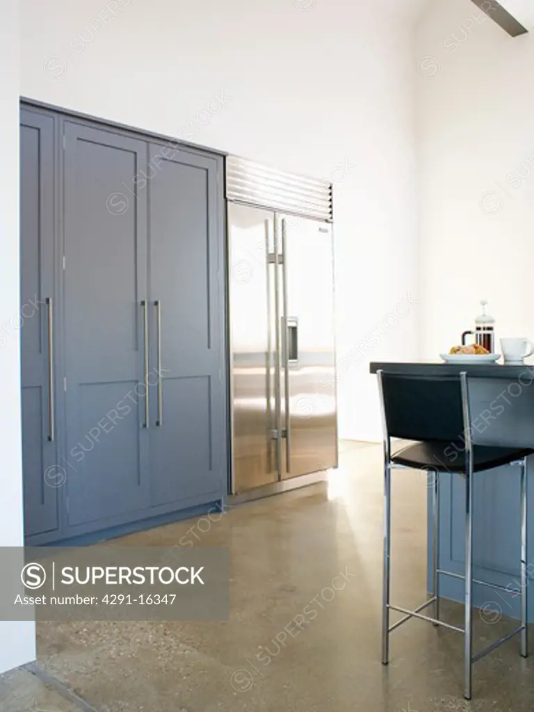 Large stainless-steel American-style fridge freezer in modern kitchen with concrete flooring