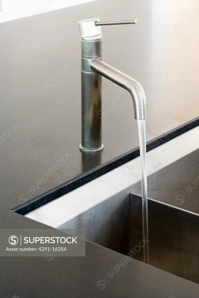 Close-up of stainless-steel tap pouring water into underset sink