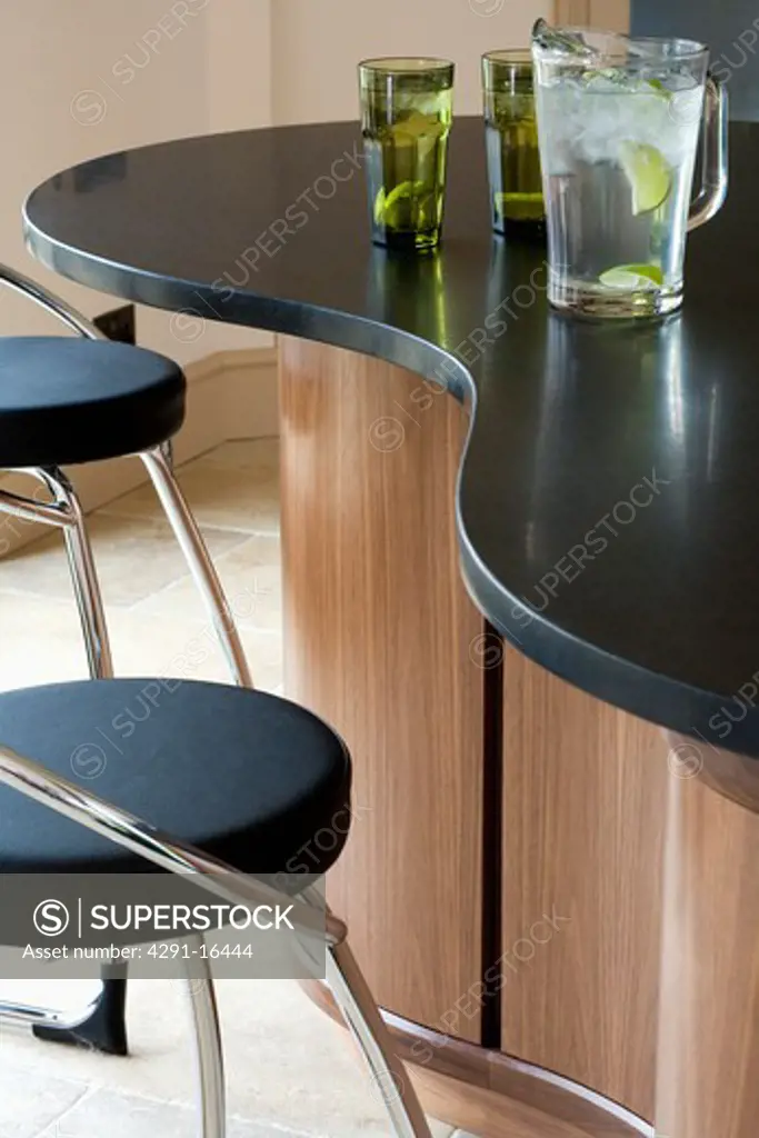 Close-up of chrome and black leather stools at breakfast bar with black granite worktop