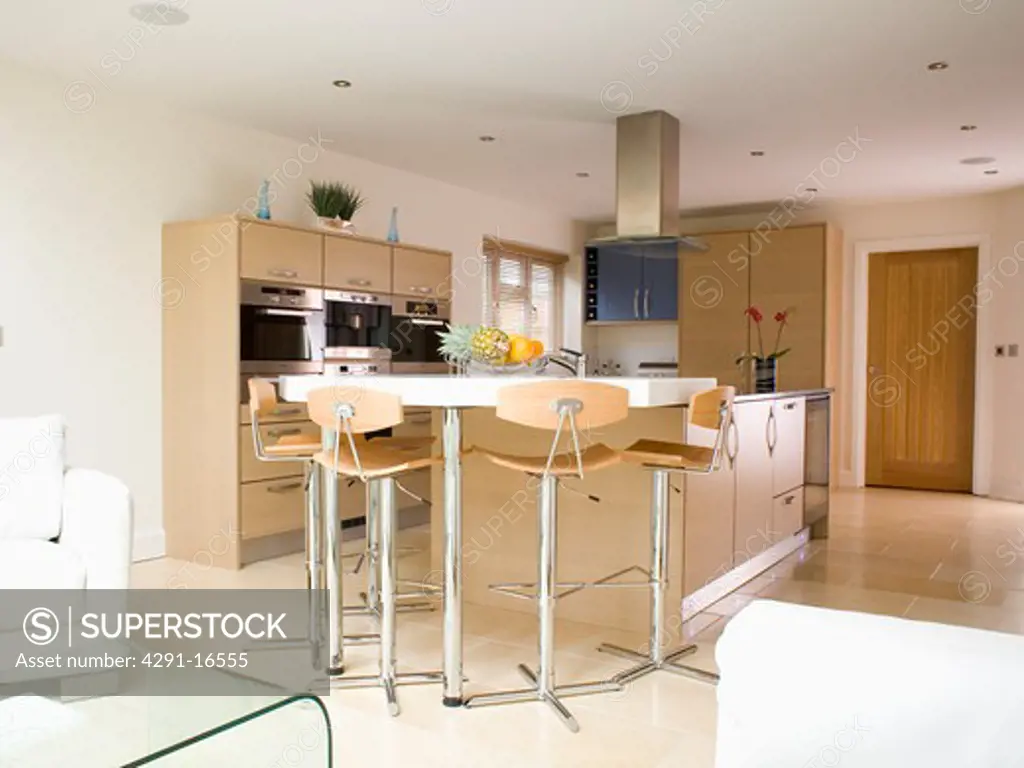 Stools at breakfast bar on island unit in large modern kitchen