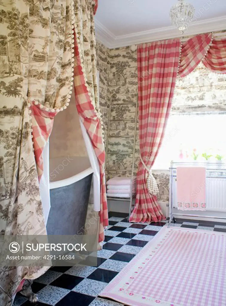 Grey Toile-de-Jouy curtains above bath in bathroom with red checked curtains on window