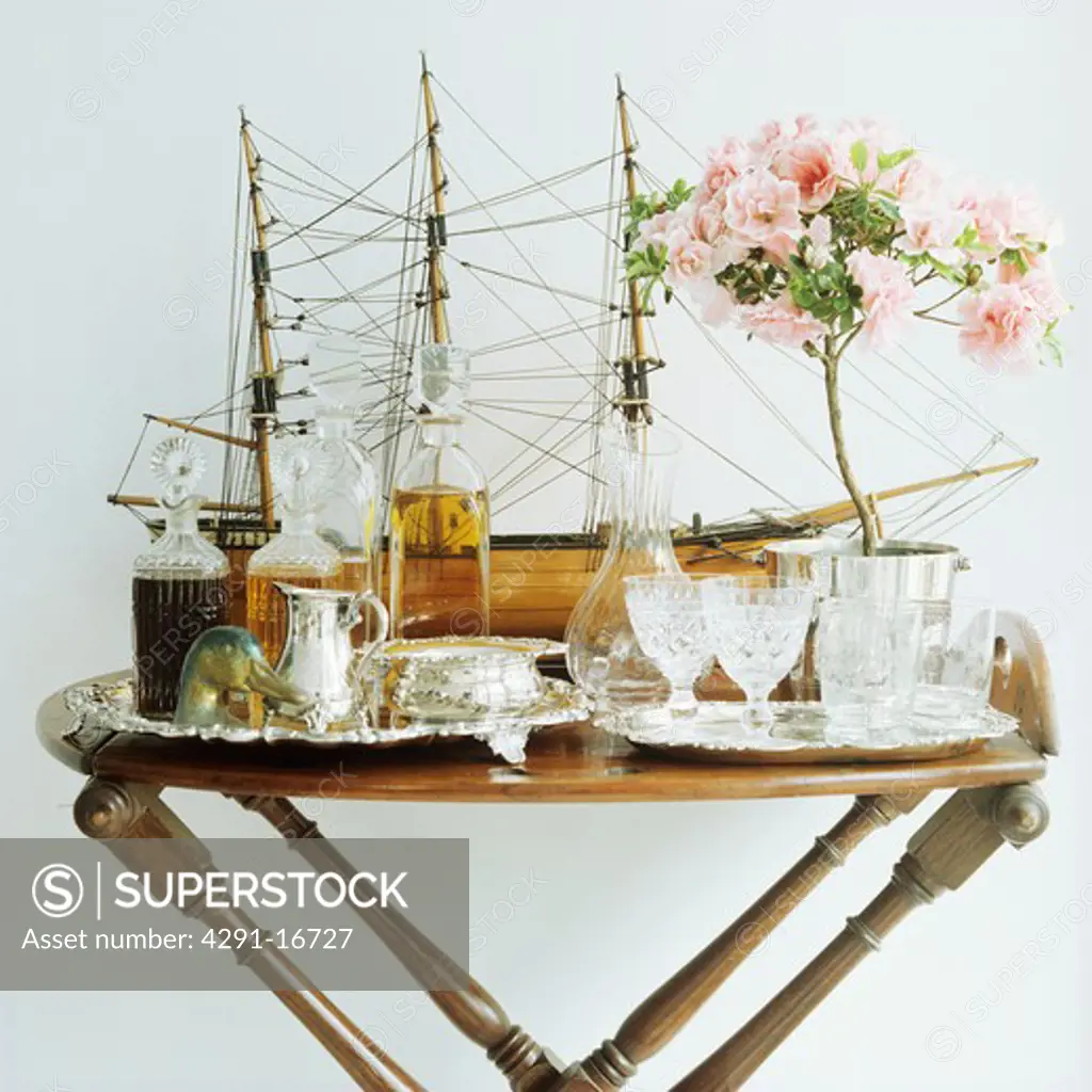 Collection of antique glasses and decanters with model sailing ship on antique table