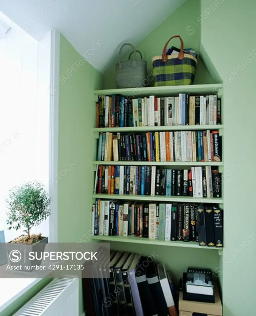 Straw baskets on alcove bookshelves in pastel green home office
