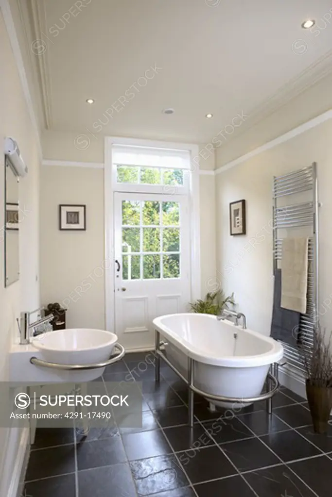 Modern rolltop bath in modern bathroom with slate flooring