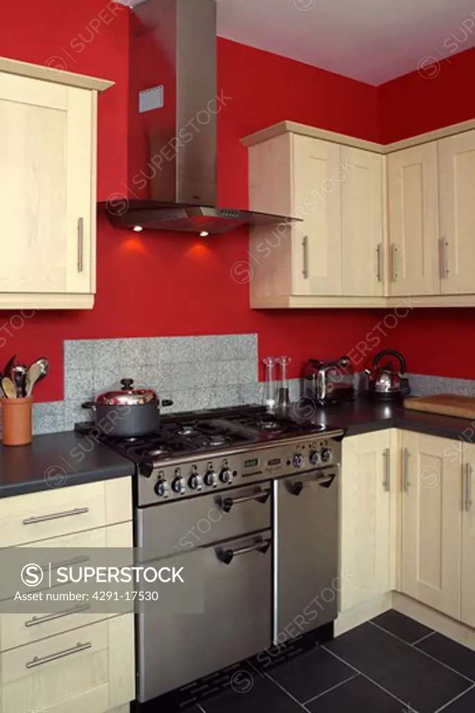 Stainless steel range oven in red kitchen with pale wood fitted cupboards