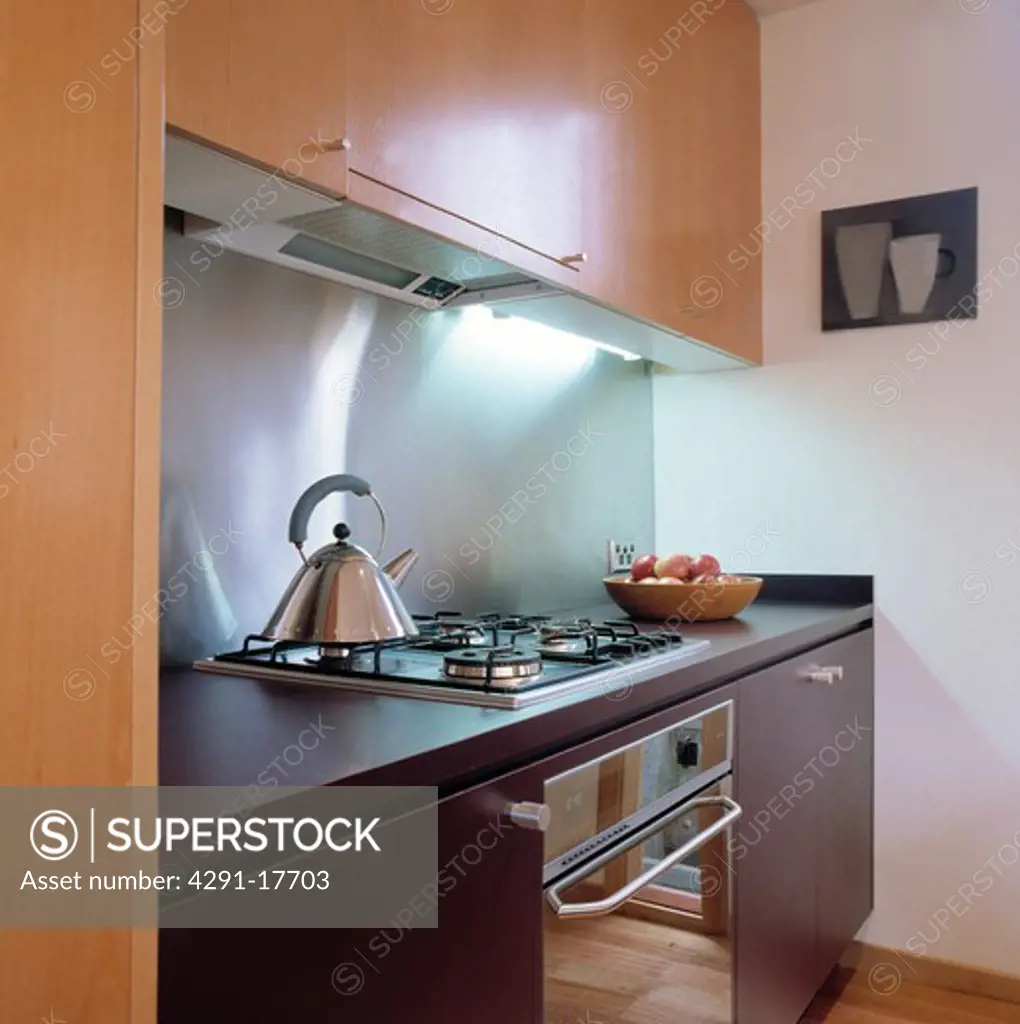 Small modern kitchen with wooden units and stainless splashback
