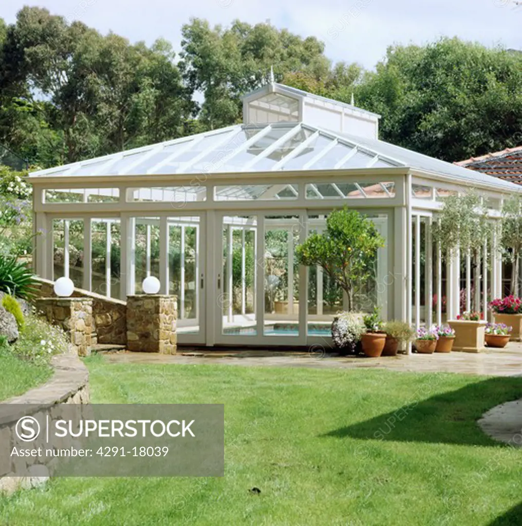 Exterior of glass building covering swimming pool set in garden