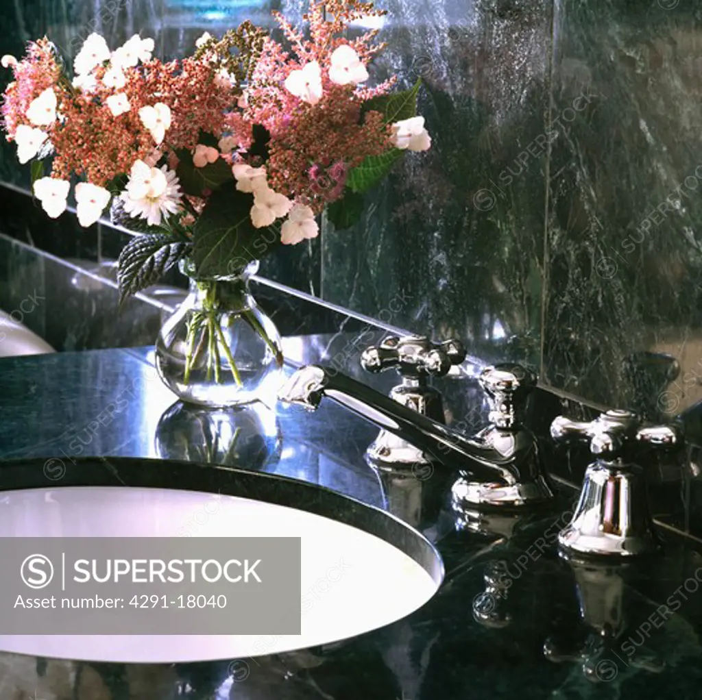 Close-up of pink flowers in vase on granite vanity unit with underset basin