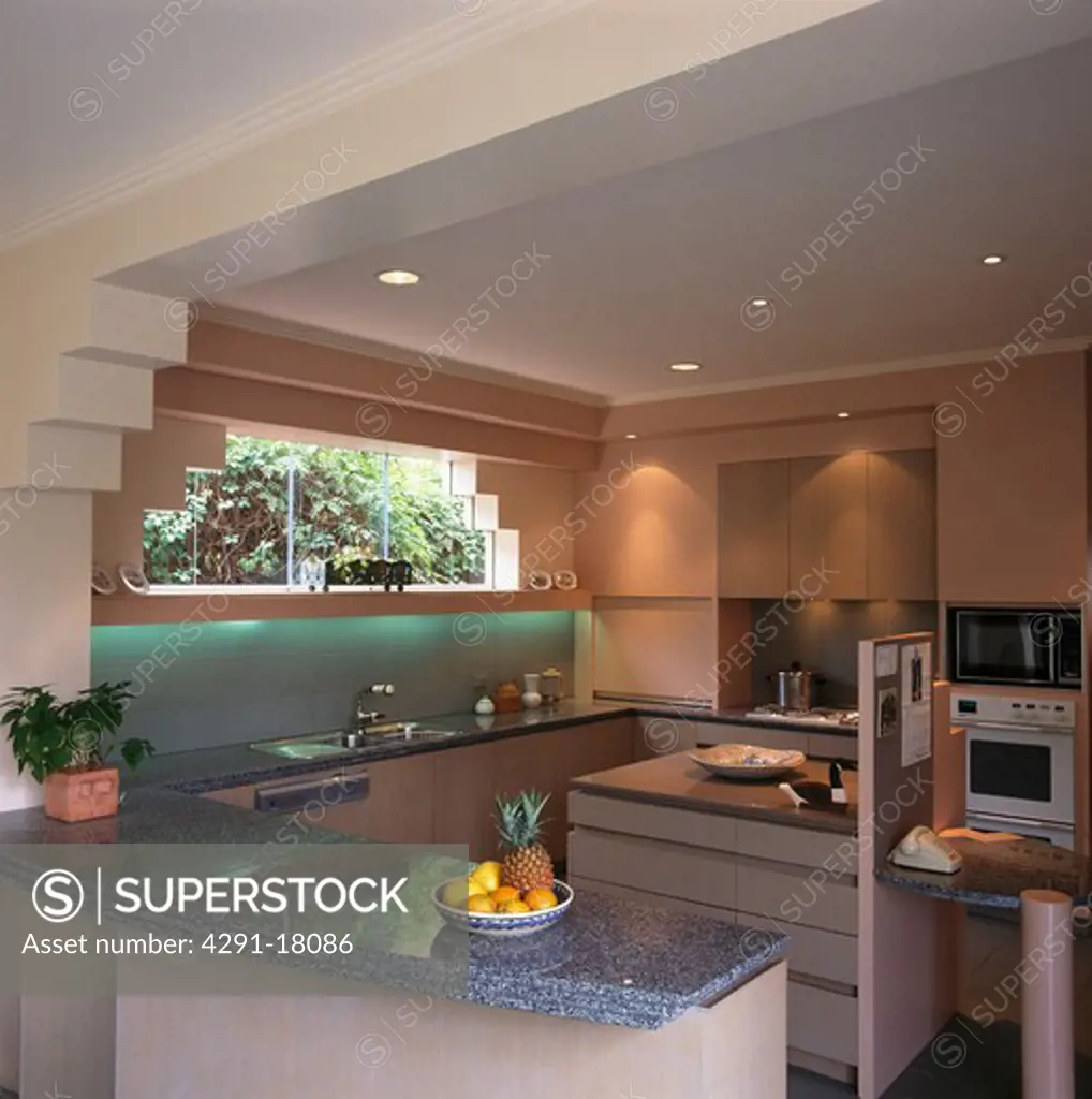 Grey granite worktop on peninsular unit in modern pink kitchen