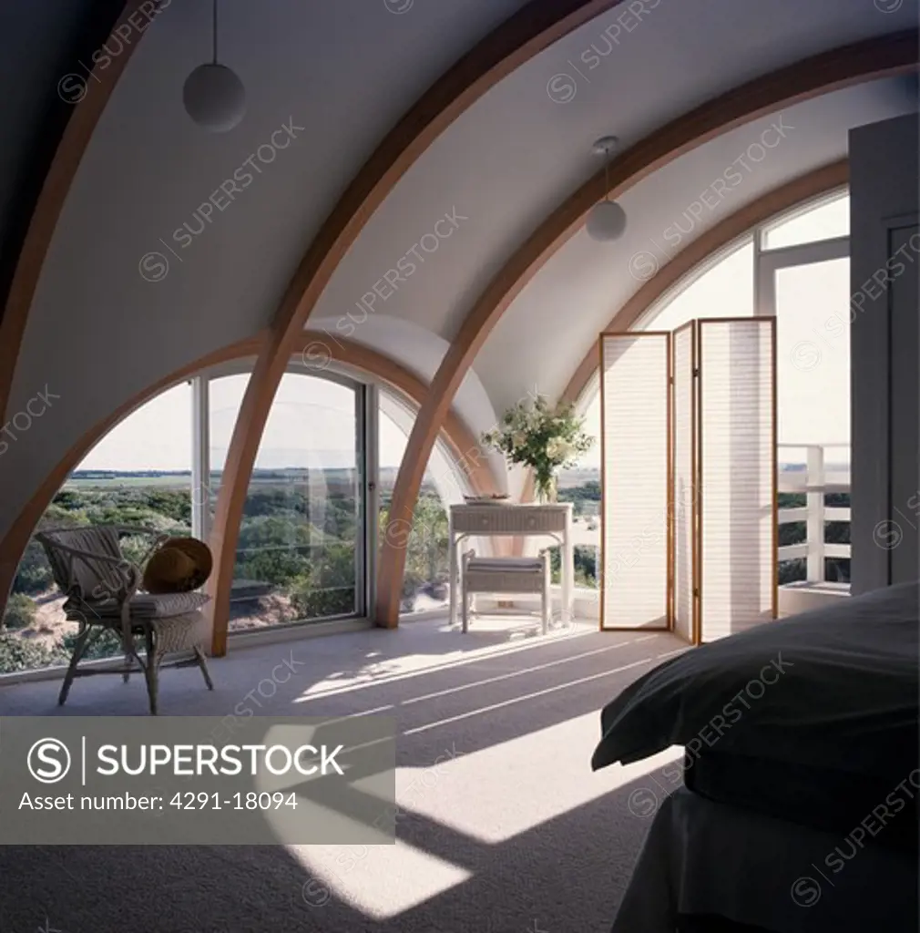 Arched window and ceiling in modern bedroom with folding white screen and grey carpet