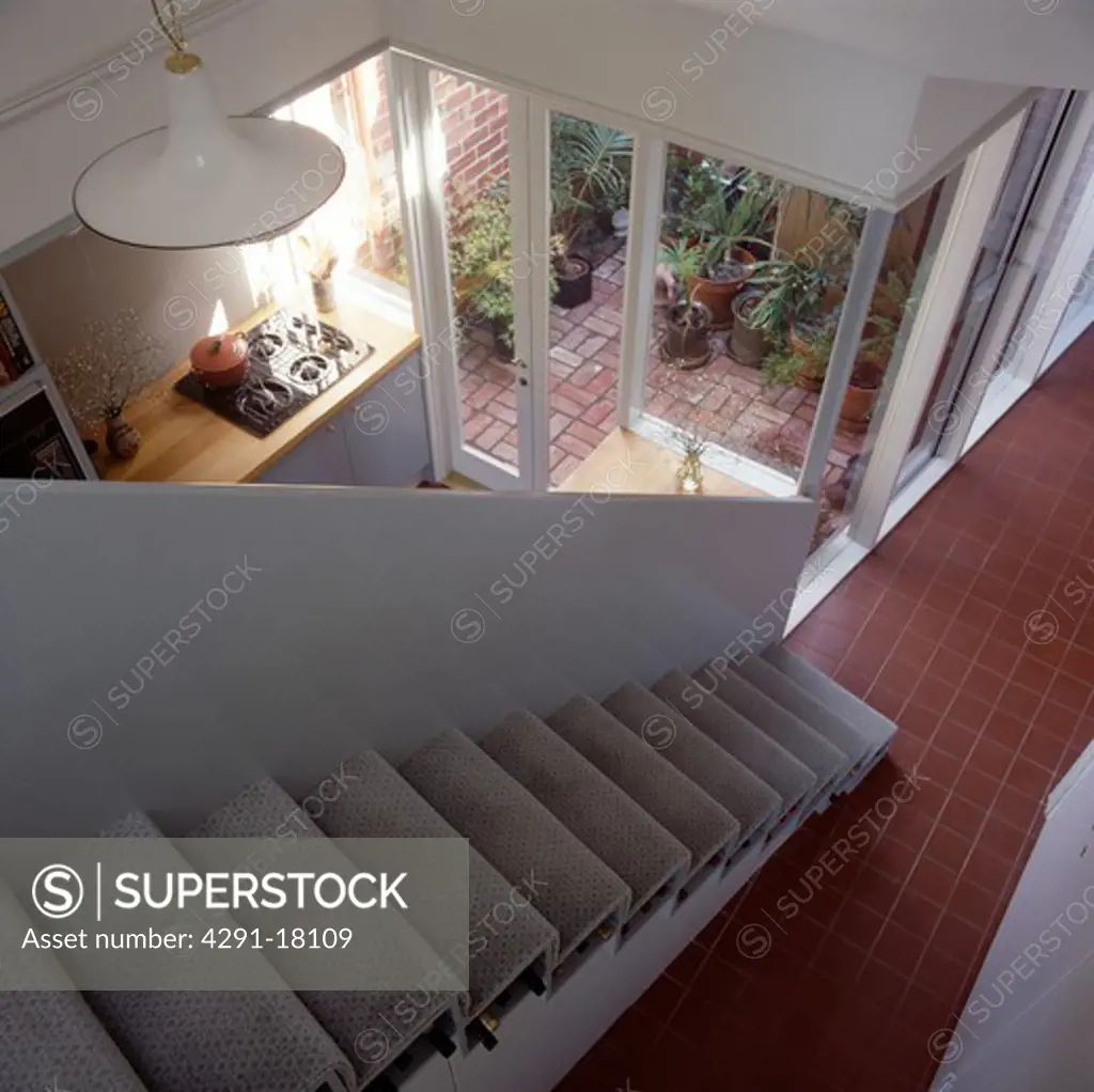 Looking down open staircase to modern white hall with tiled floor