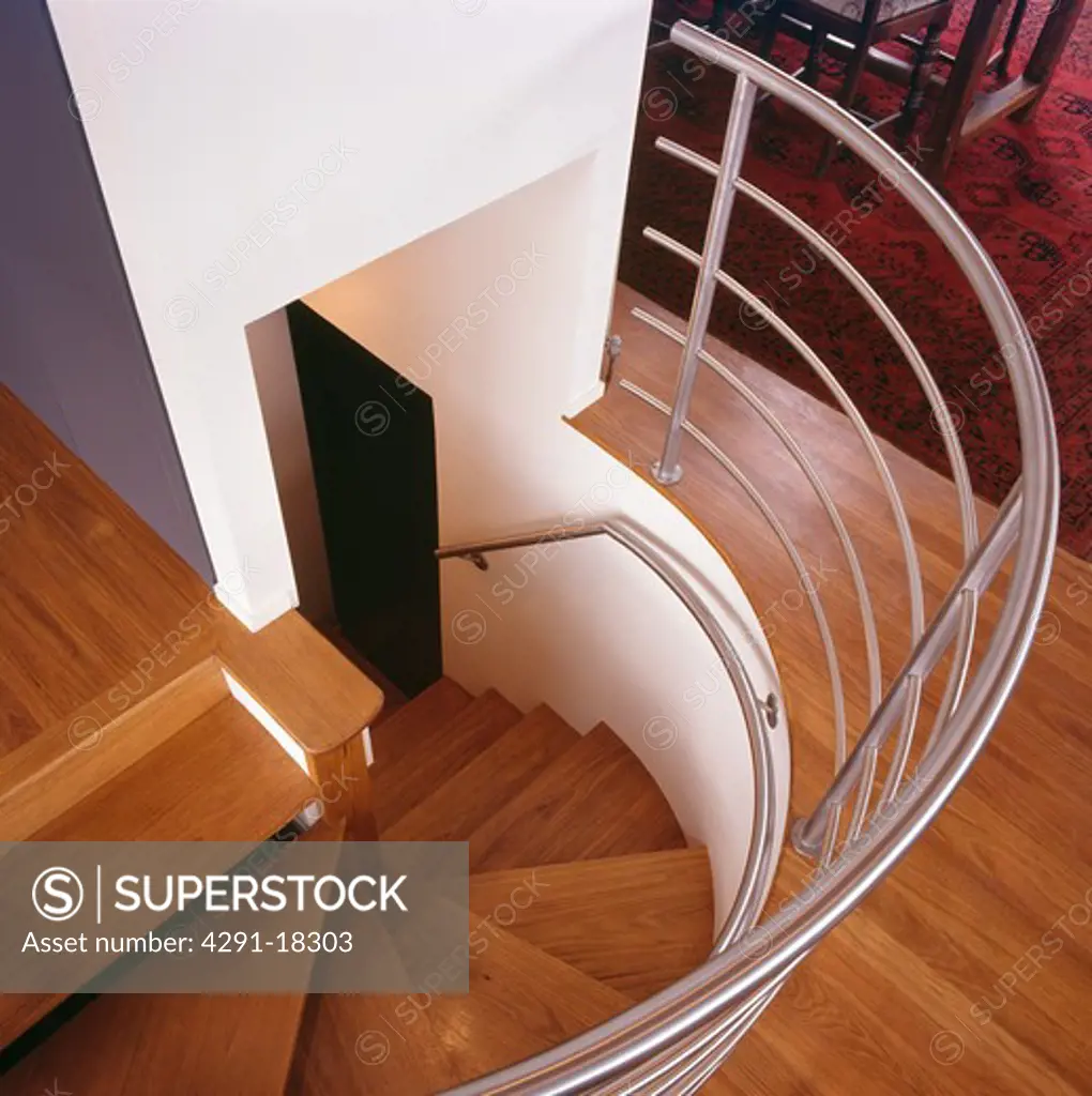 Birdseye view of staircase with curved metal bannister and wooden flooring