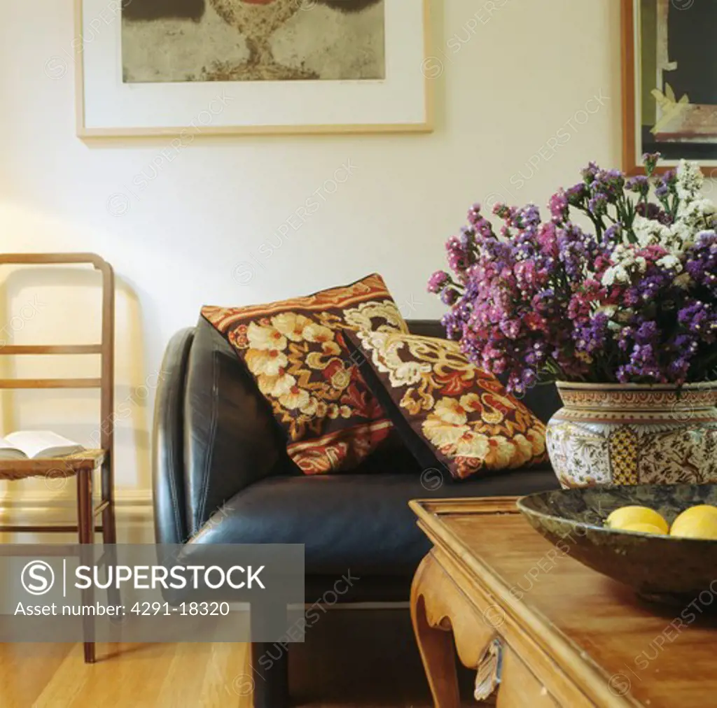 Dried flower arrangement on table in living room with tapestry cushions on leather sofa