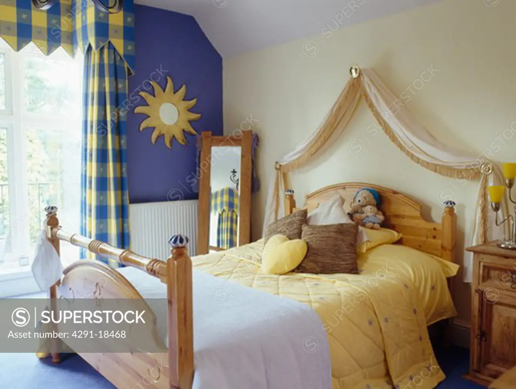 Blue and yellow checked curtains and pine bed with yellow bedlinen in small bedroom
