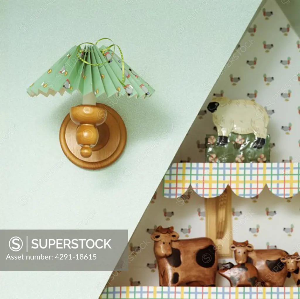 Close-up of green concertina lampshade on pine fitting beside animal ornaments on alcove shelves with edging