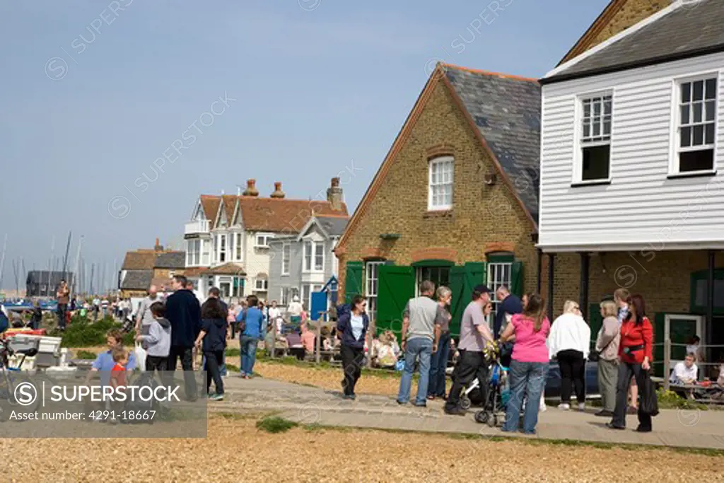 People walking on pebble beach in front of buildings on seafront at Whitstable in Kent