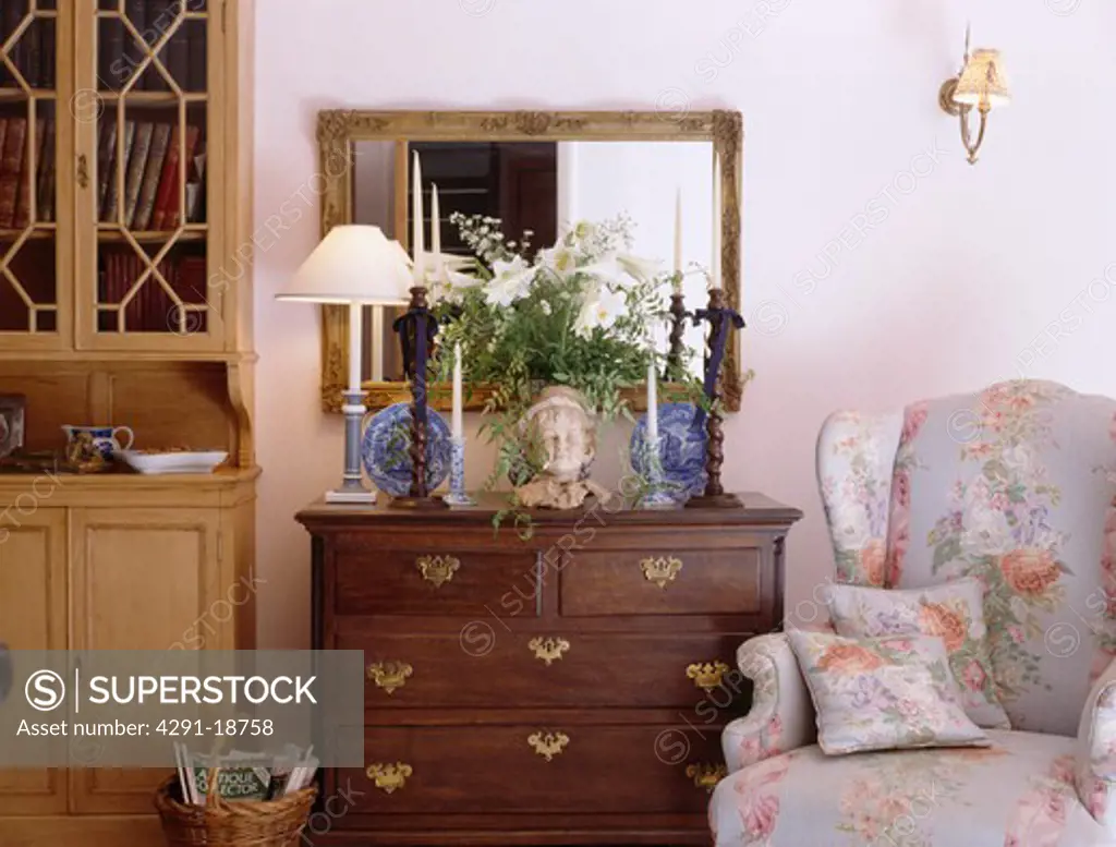 Floral wingchair beside antique chest-of-drawers in cottage living room
