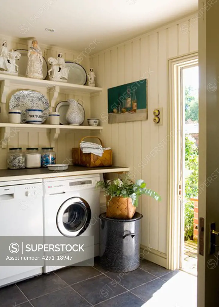 Collection of Staffordshire china on shelves above dishwasher and washing machine in country kitchen