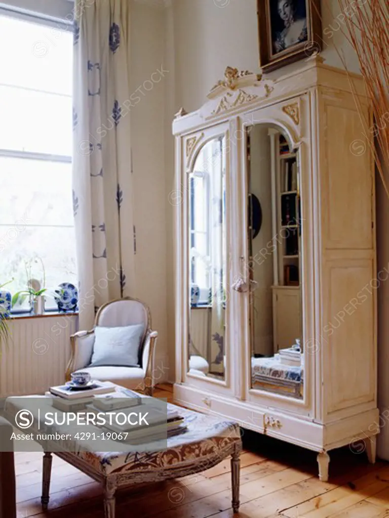 Mirror-fronted painted white cupboard in white living room