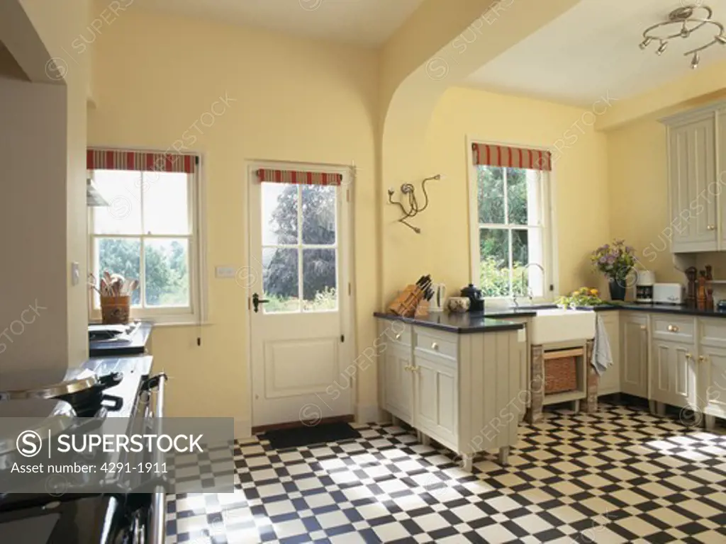 Black and white vinyl flooring in pastel yellow country kitchen