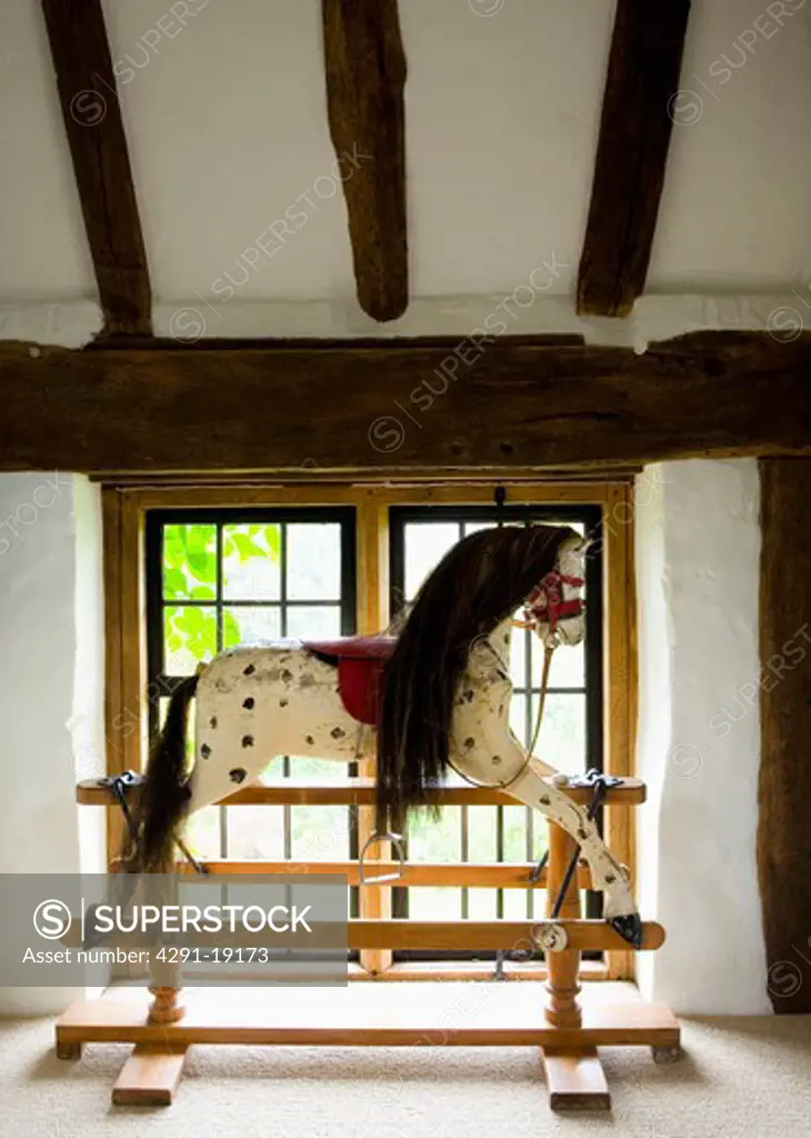 Antique swing-stand rocking horse in front of landing window