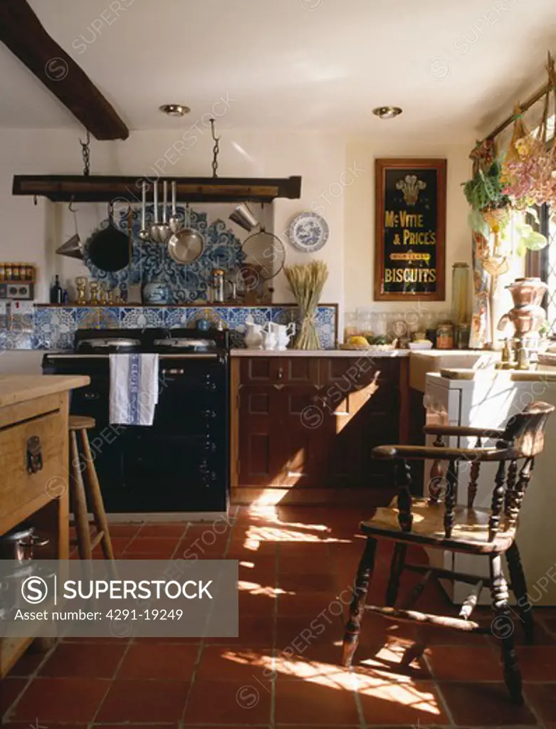 Black Aga below blue and white tiles in country kitchen with terracotta floor tiles & vintage McVitie Biscuit sign