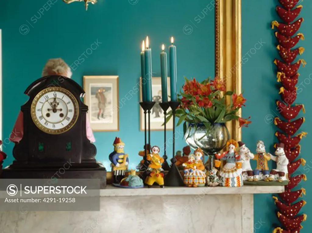 Close-up of clock and ceramic folk ornaments on mantelpiece