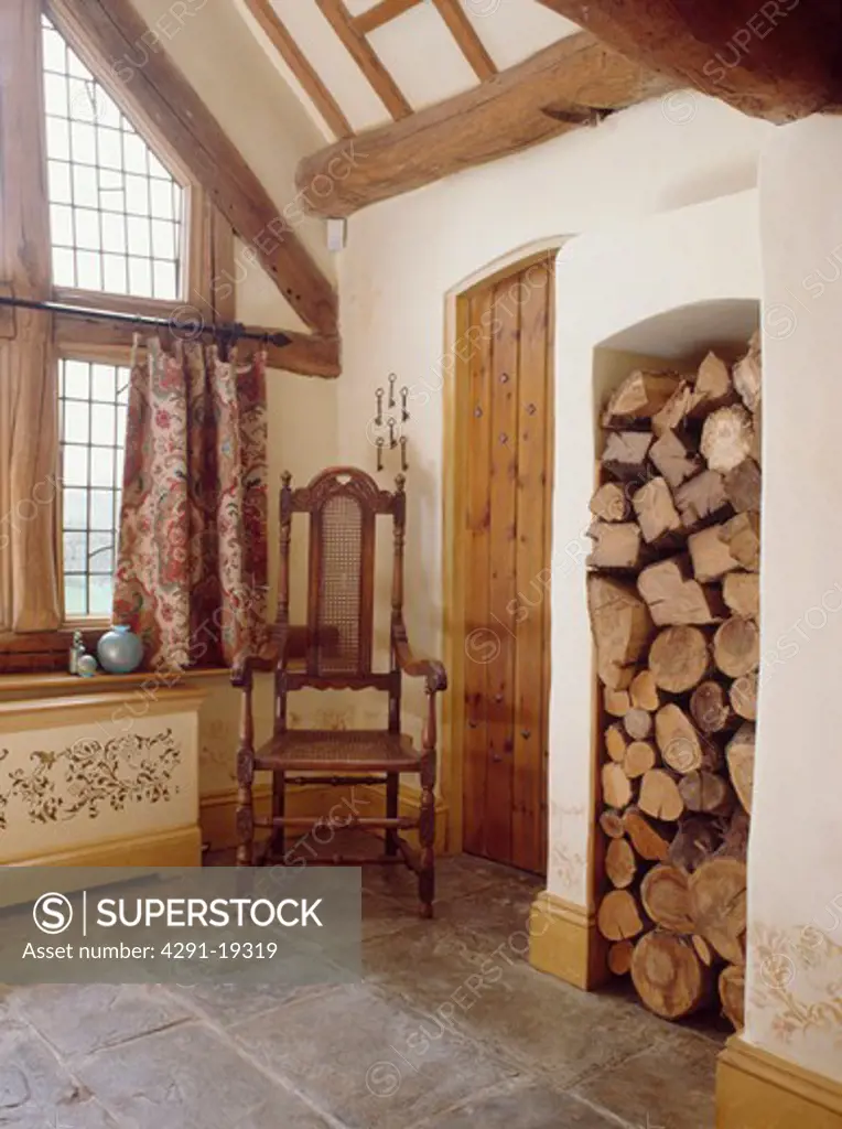 Jacobean chair in corner of country hall with stone floor and logs stored in tall alcove