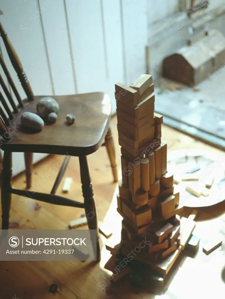 Close-up of wooden chair and pile of child's old wooden building blocks