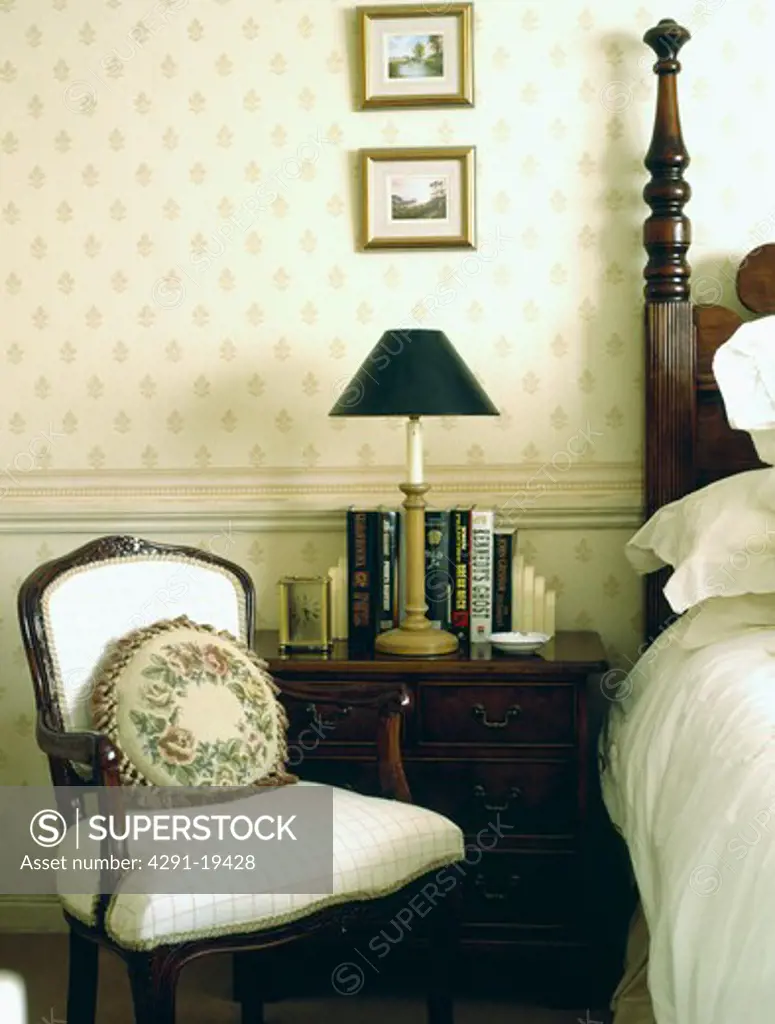 Tapestry cushion on small Victorian chair in neutral bedroom with wallpaper