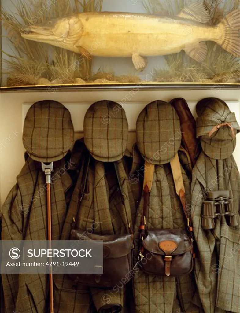 Close-up of fish in glass box above country coats and caps