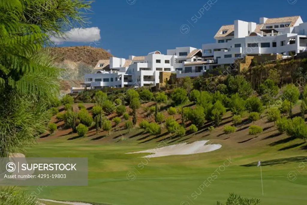 Modern white Spanish holiday village on hilltop above golf course