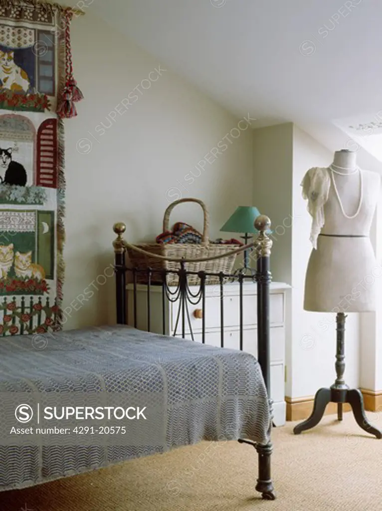 Dressmaker's dummy in white attic bedroom with grey bedcover on old brass bed